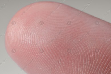 Finger with friction ridges on light blue background, macro view Photo of Finger with friction ridges on light blue background, macro view