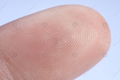 Finger with friction ridges on light blue background, macro view Photo of Finger with friction ridges on light blue background, macro view