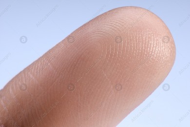 Finger with friction ridges on light blue background, macro view Photo of Finger with friction ridges on light blue background, macro view