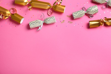 Open and closed Christmas crackers with shiny confetti on pink background, flat lay. Space for text Photo of Open and closed Christmas crackers with shiny confetti on pink background, flat lay. Space for text