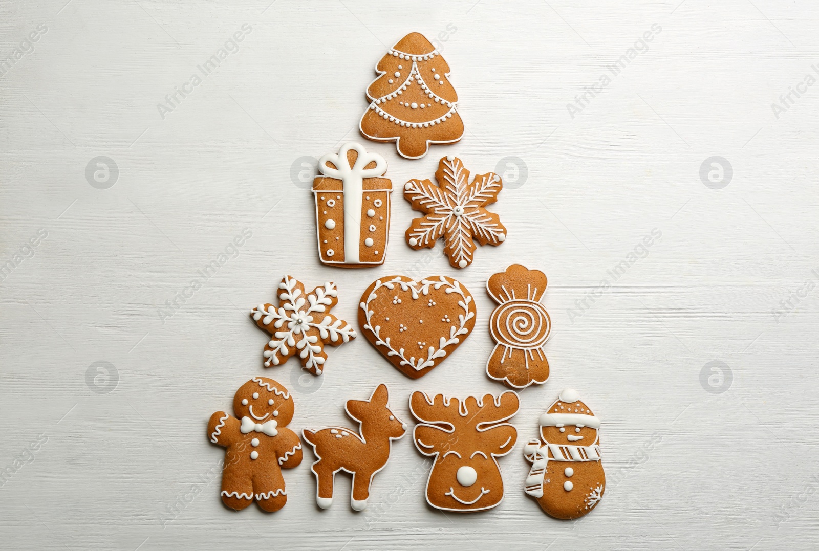 Christmas tree shape made of delicious decorated gingerbread cookies on white wooden table, flat lay Photo of Christmas tree shape made of delicious decorated gingerbread cookies on white wooden table, flat lay