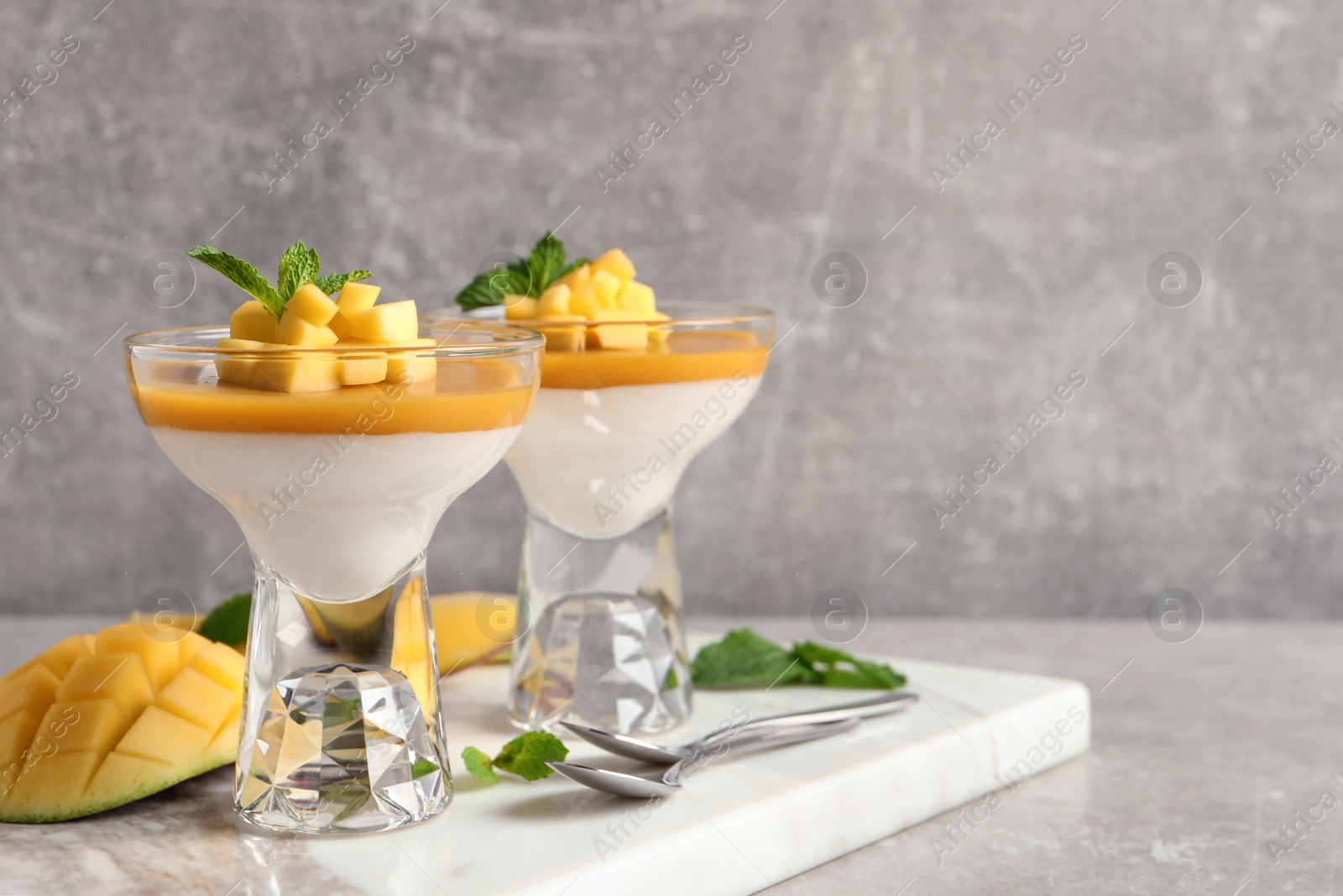 Delicious panna cotta with mango coulis served on light grey table. Space for text Photo of Delicious panna cotta with mango coulis served on light grey table. Space for text