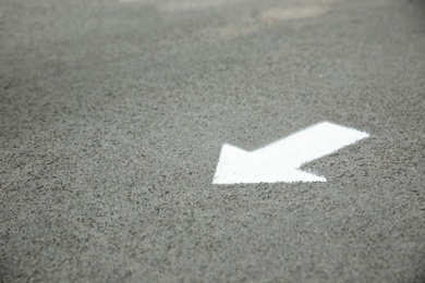 White arrow painted on asphalt. Space for text Photo of White arrow painted on asphalt. Space for text