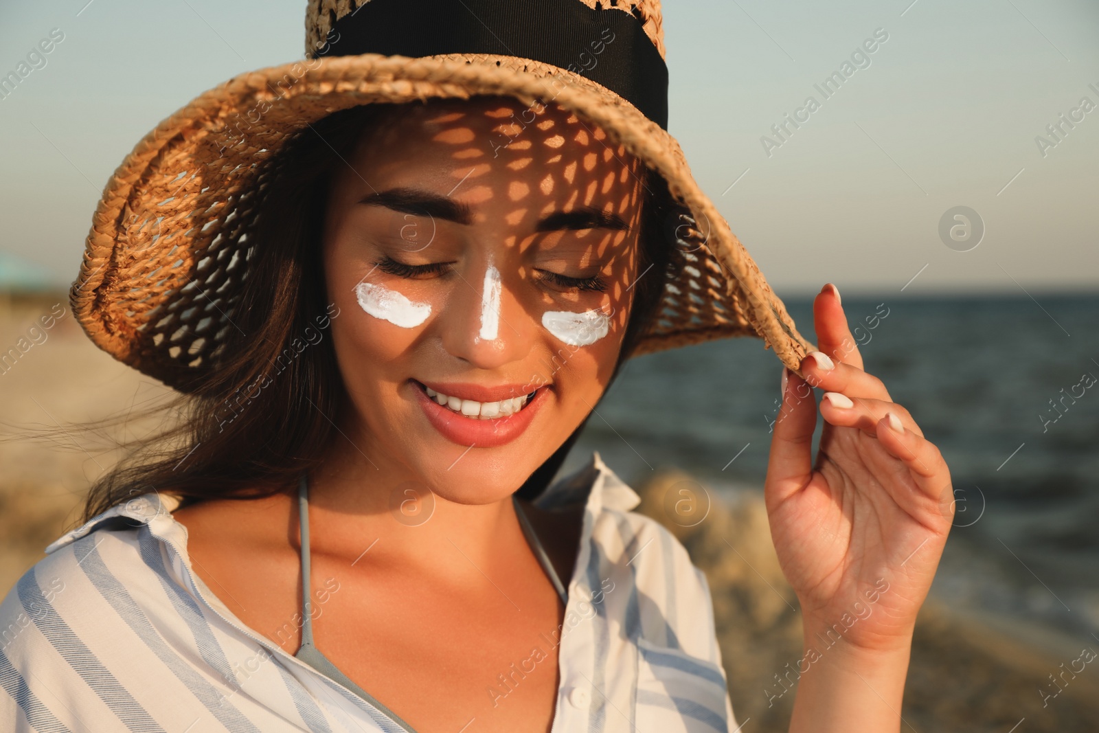 Happy young woman with sun protection cream on face at beach Photo of Happy young woman with sun protection cream on face at beach