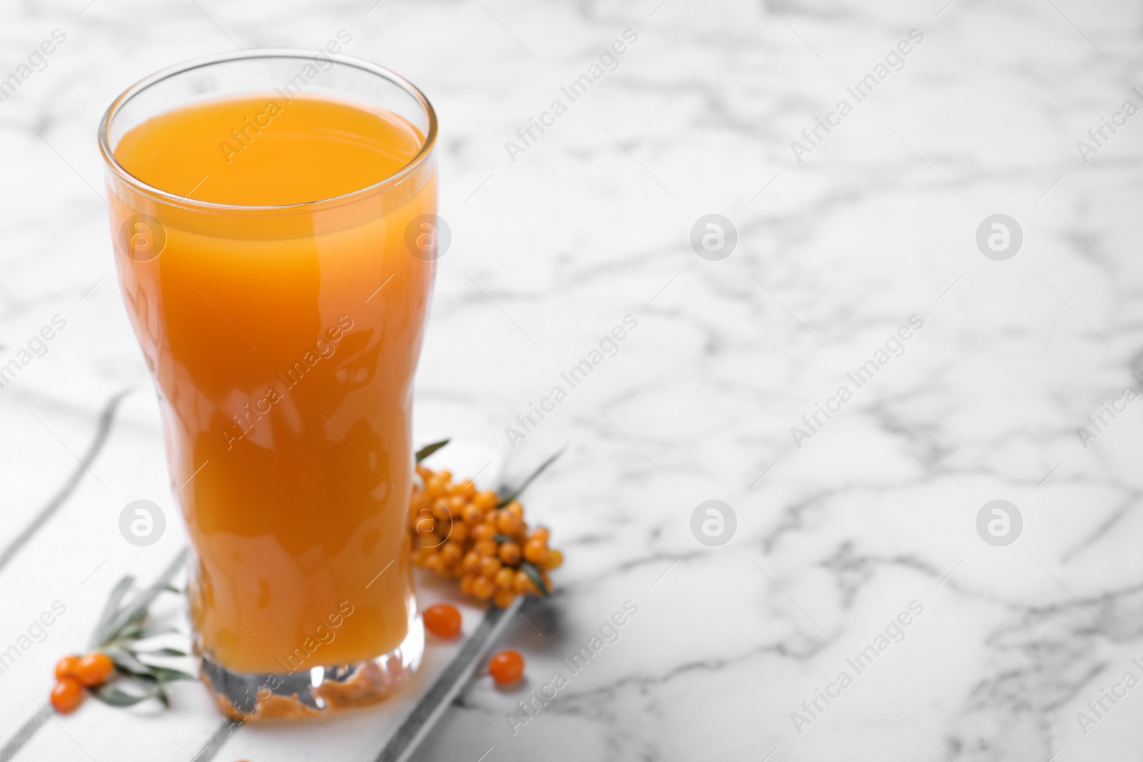 Photo of Delicious sea buckthorn juice on white marble table. Space for text