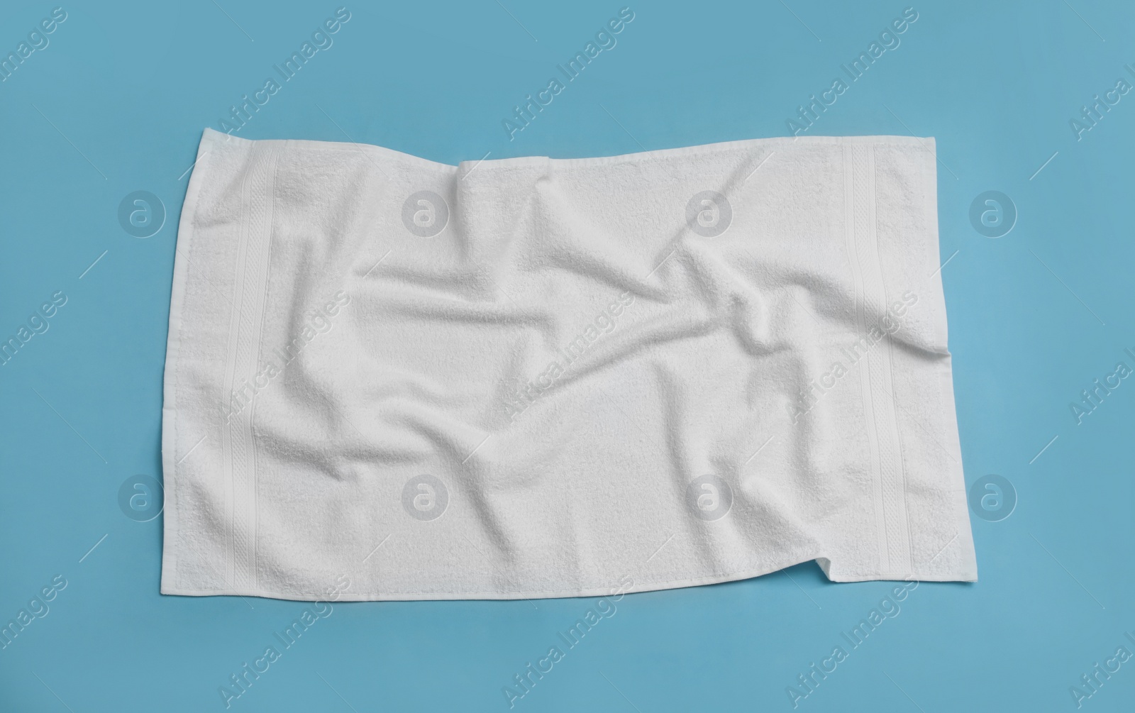 Crumpled white beach towel on light blue background, top view Photo of Crumpled white beach towel on light blue background, top view