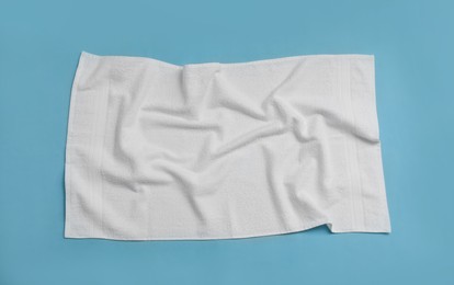 Crumpled white beach towel on light blue background, top view Photo of Crumpled white beach towel on light blue background, top view