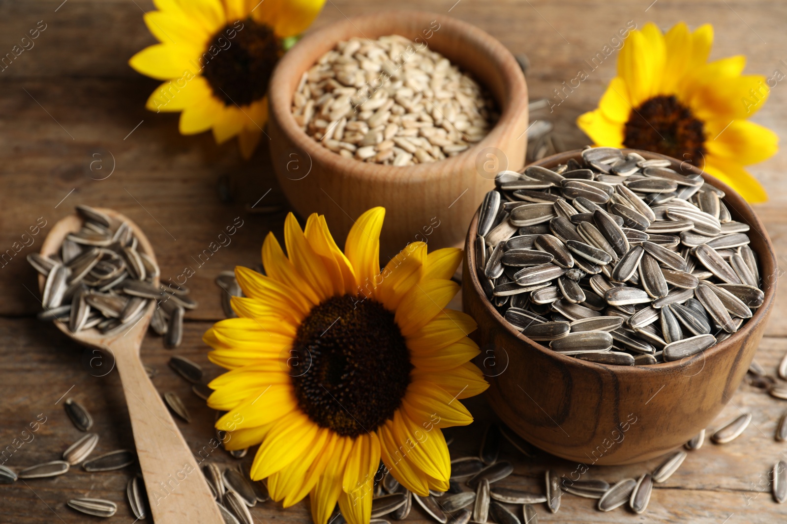 Organic sunflower seeds and flowers on wooden table Photo of Organic sunflower seeds and flowers on wooden table