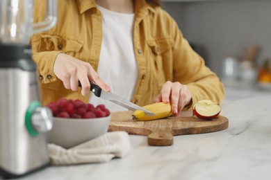Woman preparing ingredients for tasty smoothie at white marble table in kitchen, closeup Photo of Woman preparing ingredients for tasty smoothie at white marble table in kitchen, closeup
