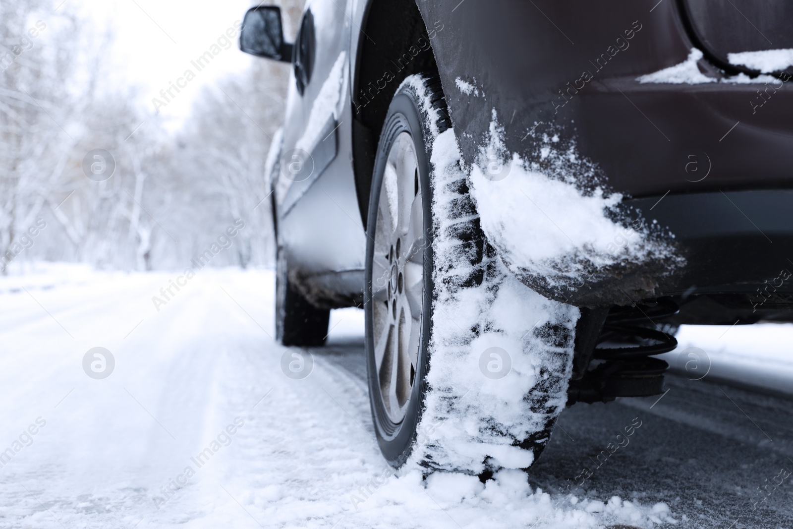 Modern car with winter tires on snowy road, closeup Photo of Modern car with winter tires on snowy road, closeup