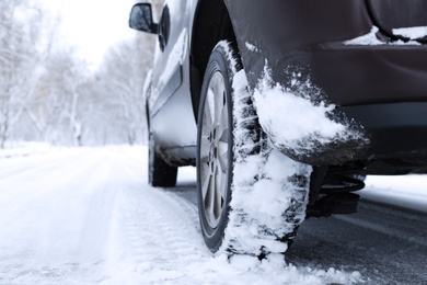 Modern car with winter tires on snowy road, closeup Photo of Modern car with winter tires on snowy road, closeup