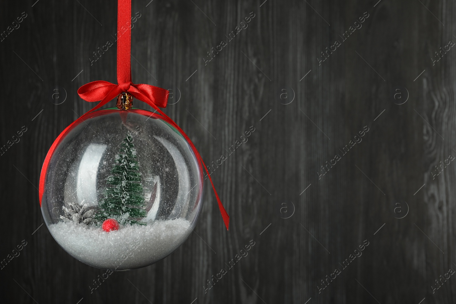 Beautiful Christmas snow globe hanging on black wooden background, space for text Photo of Beautiful Christmas snow globe hanging on black wooden background, space for text