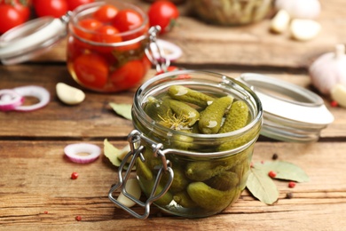 Glass jar of pickled cucumbers on wooden table Photo of Glass jar of pickled cucumbers on wooden table