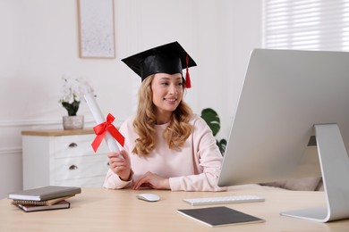 Happy student with graduation hat and diploma at workplace in office Photo of Happy student with graduation hat and diploma at workplace in office