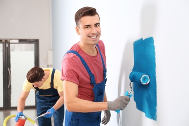 Male decorator painting wall with roller indoors Photo of Male decorator painting wall with roller indoors