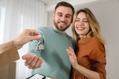 Real estate agent giving key to happy young couple in new house, focus on hands Photo of Real estate agent giving key to happy young couple in new house, focus on hands