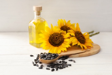 Sunflowers, bottle of oil and seeds on white wooden table Photo of Sunflowers, bottle of oil and seeds on white wooden table