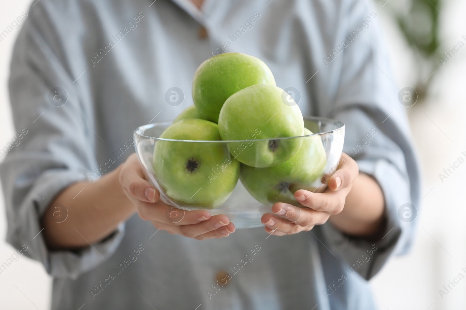 Woman holding bowl with ripe green apples, closeup Photo of Woman holding bowl with ripe green apples, closeup