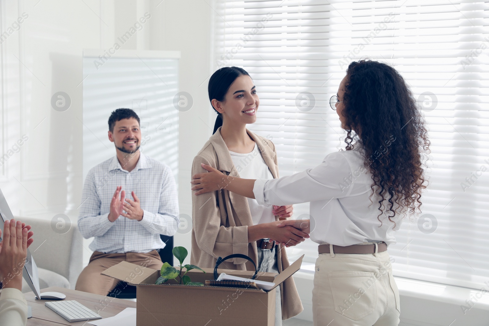 Boss shaking hand with new employee and coworkers applauding in office Photo of Boss shaking hand with new employee and coworkers applauding in office