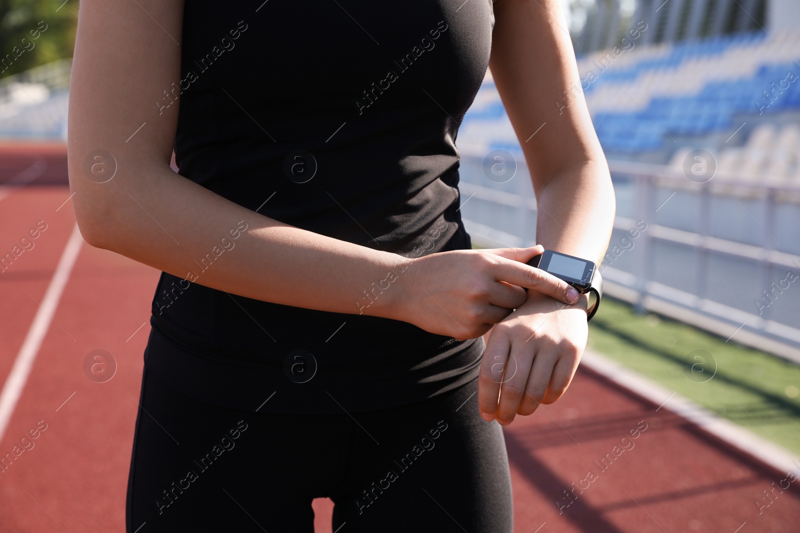 Woman checking fitness tracker after training at stadium, closeup Photo of Woman checking fitness tracker after training at stadium, closeup