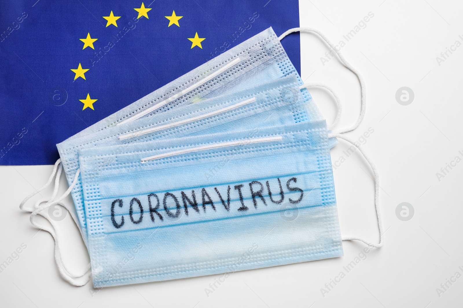 Protective masks and European Union flag on white background, flat lay. Coronavirus outbreak Photo of Protective masks and European Union flag on white background, flat lay. Coronavirus outbreak