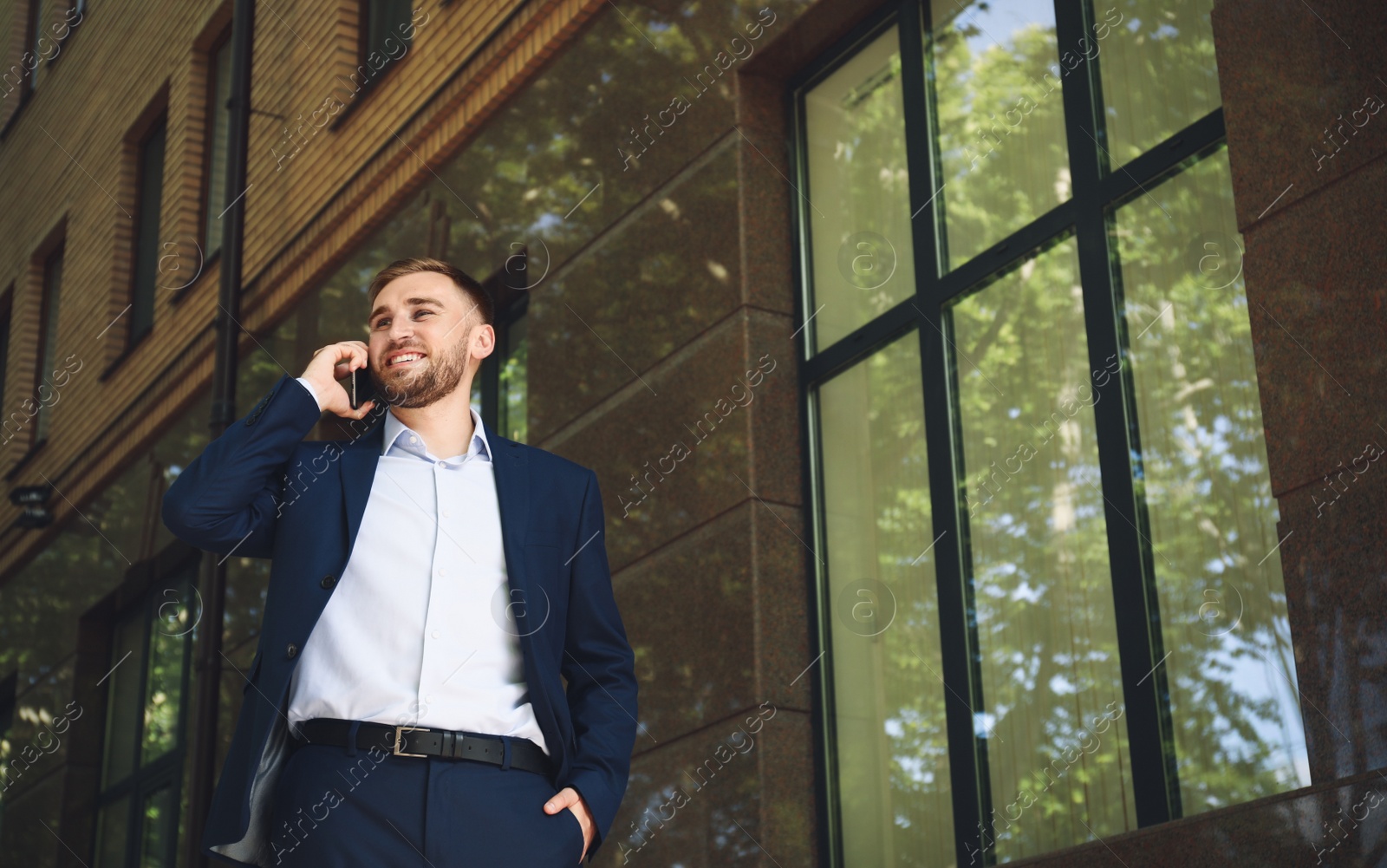 Young man talking on smartphone on city street Photo of Young man talking on smartphone on city street