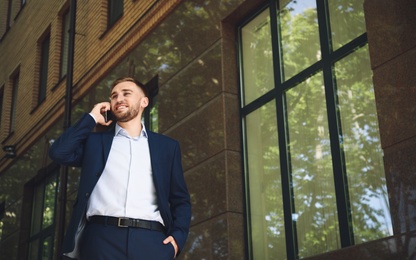 Young man talking on smartphone on city street Photo of Young man talking on smartphone on city street