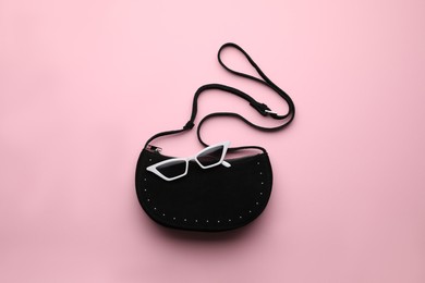 Stylish woman's bag and sunglasses on pink background, top view Photo of Stylish woman's bag and sunglasses on pink background, top view