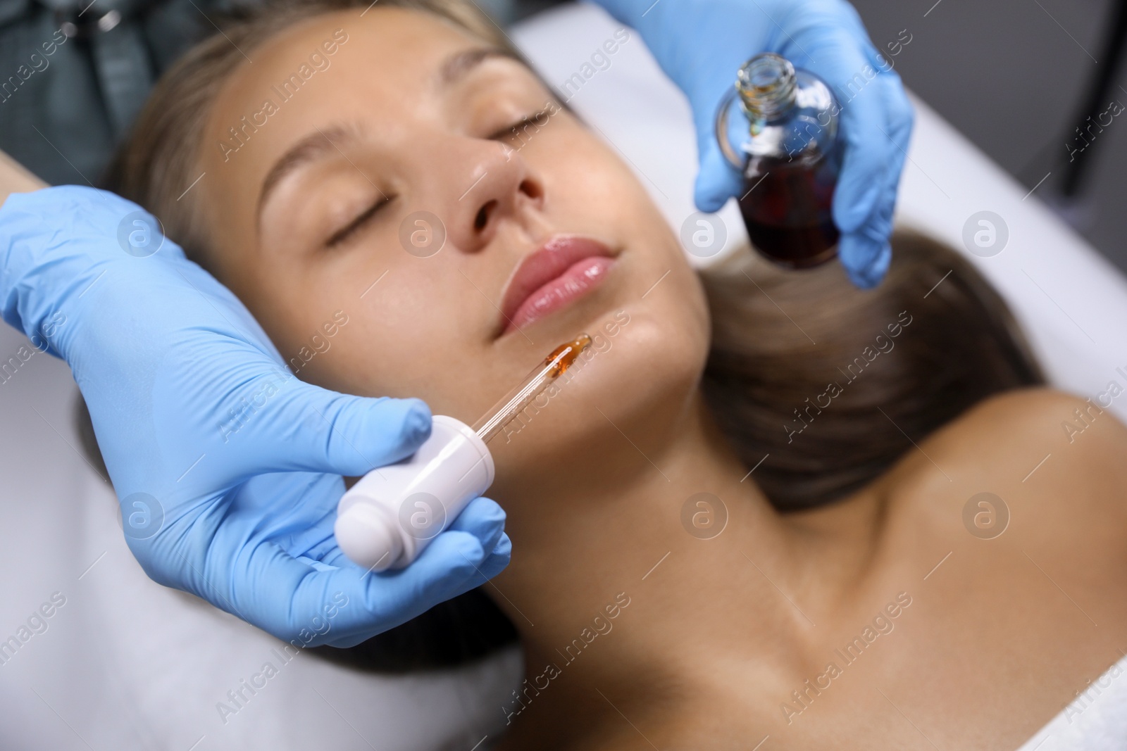 Cosmetologist applying serum on client's face in salon Photo of Cosmetologist applying serum on client's face in salon