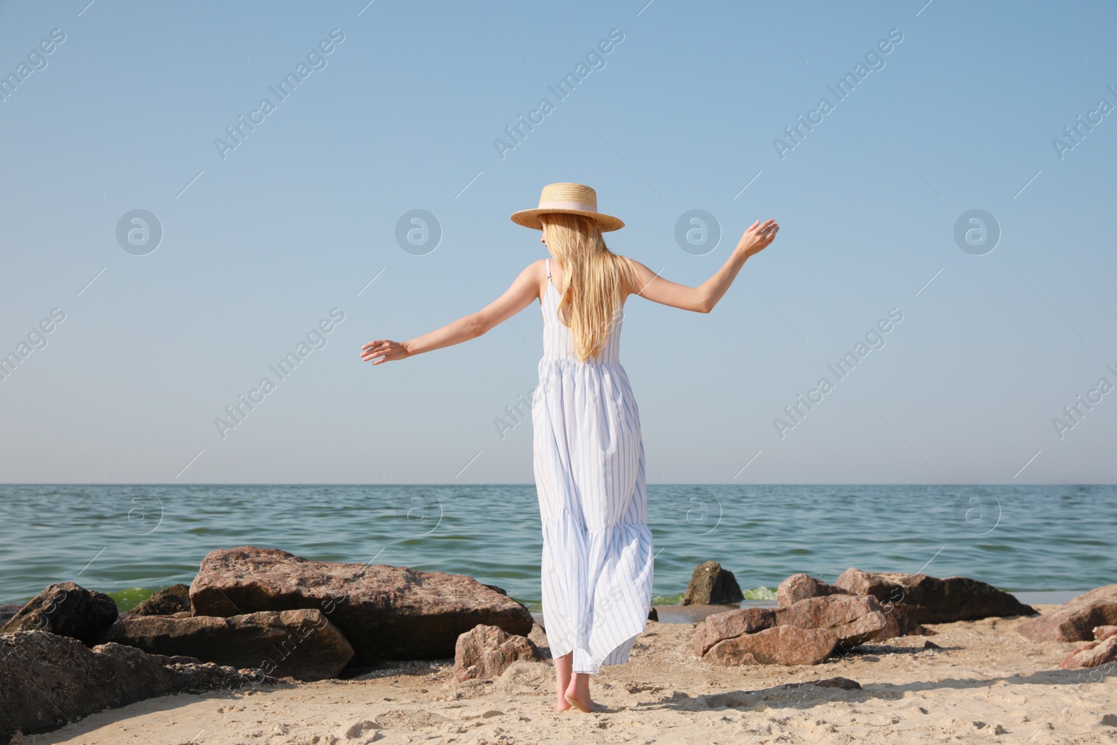 Young woman near sea on sunny day in summer, back view Photo of Young woman near sea on sunny day in summer, back view