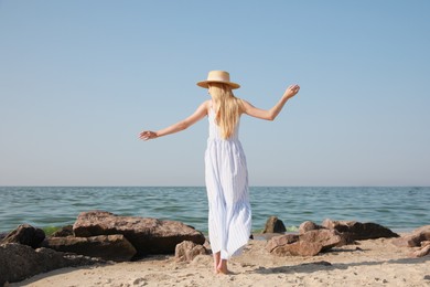 Young woman near sea on sunny day in summer, back view Photo of Young woman near sea on sunny day in summer, back view