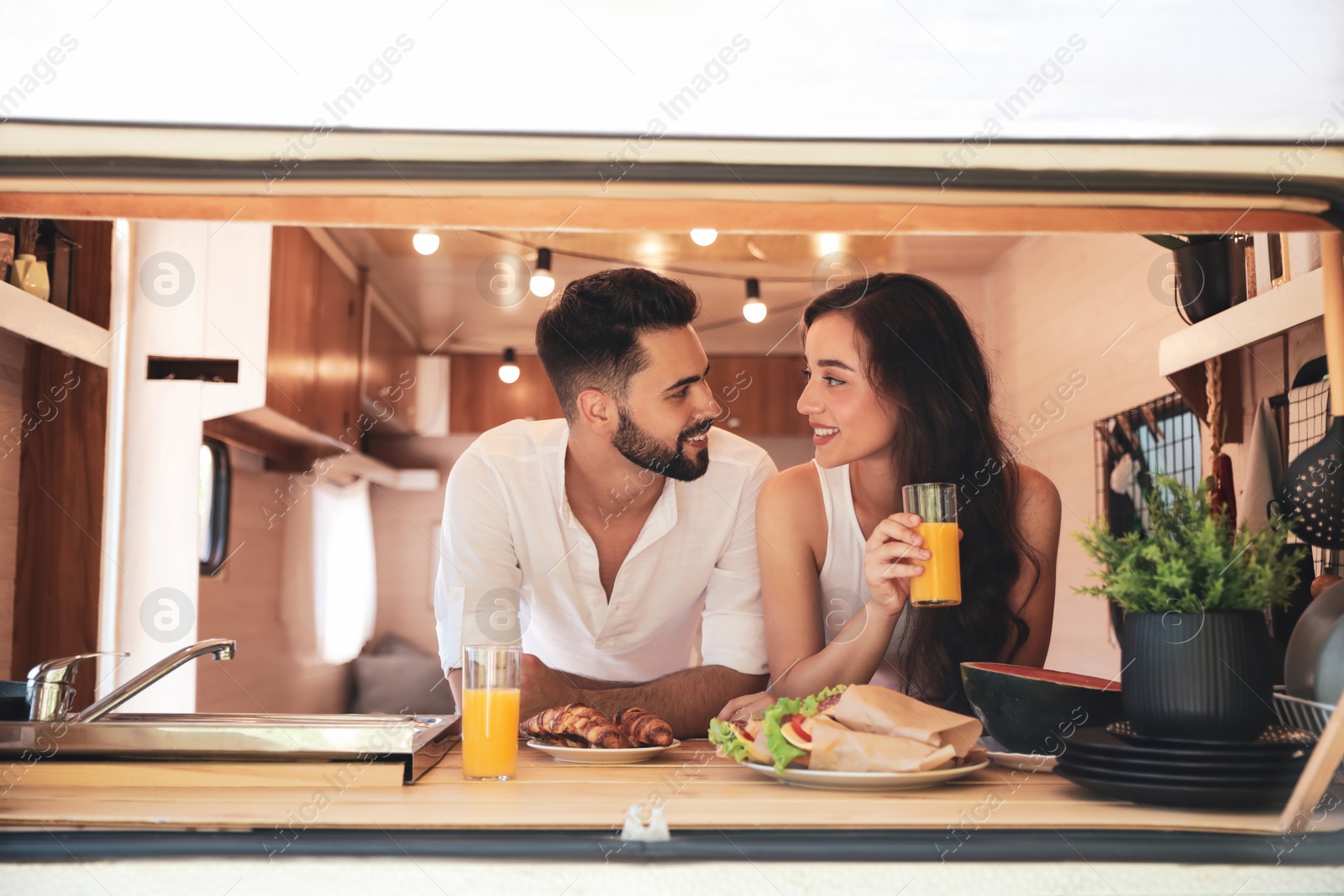Photo of Happy young couple having breakfast in trailer. Camping vacation