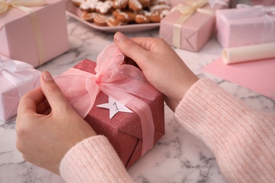 Woman with gift box at white marble table, closeup. Creating advent calendar Photo of Woman with gift box at white marble table, closeup. Creating advent calendar