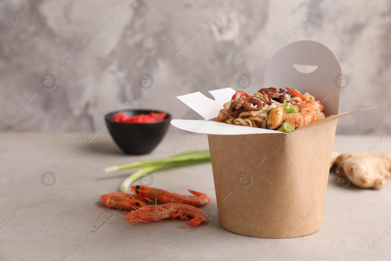 Box of wok noodles with seafood on light table. Space for text Photo of Box of wok noodles with seafood on light table. Space for text