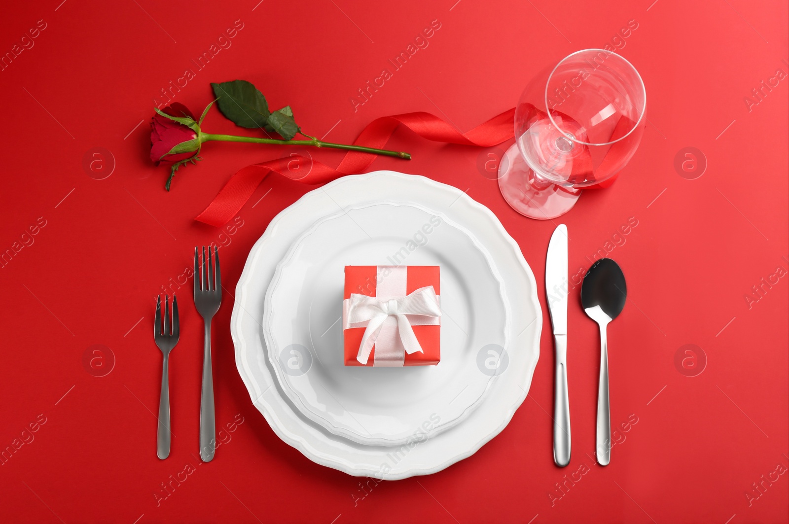 Beautiful table setting for Valentine's Day dinner on red background, flat lay Photo of Beautiful table setting for Valentine's Day dinner on red background, flat lay