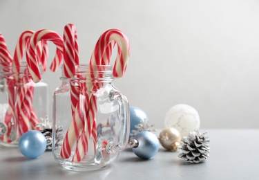 Candy canes and Christmas decor on light grey table, space for text Photo of Candy canes and Christmas decor on light grey table, space for text