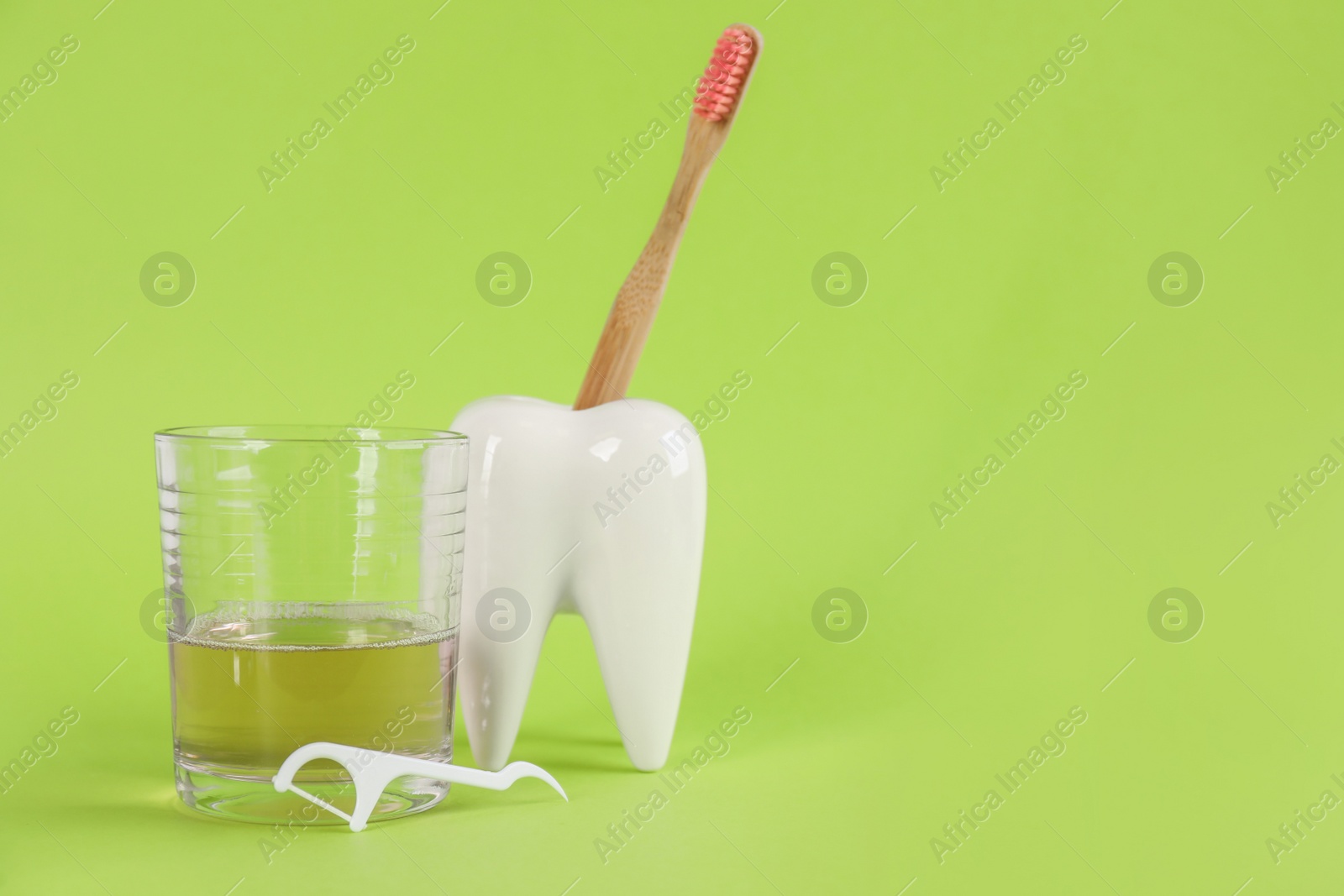 Mouthwash, toothbrush, holder and dental floss pick on light green background, space for text Photo of Mouthwash, toothbrush, holder and dental floss pick on light green background, space for text