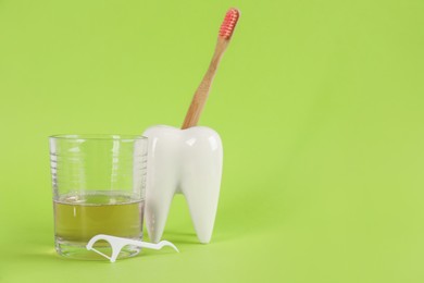 Mouthwash, toothbrush, holder and dental floss pick on light green background, space for text Photo of Mouthwash, toothbrush, holder and dental floss pick on light green background, space for text