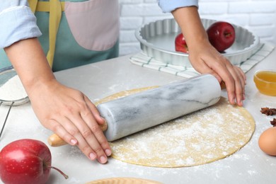 Woman rolling dough for apple pie at light grey table, closeup Photo of Woman rolling dough for apple pie at light grey table, closeup