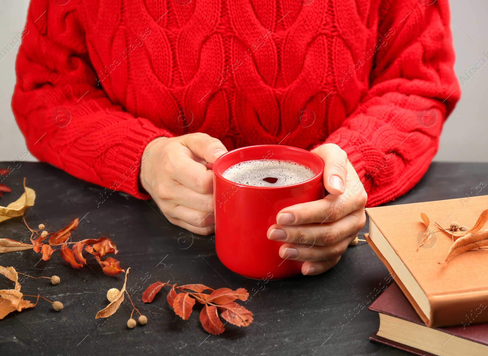 Woman with cup of hot drink at black table, closeup. Cozy autumn atmosphere Photo of Woman with cup of hot drink at black table, closeup. Cozy autumn atmosphere