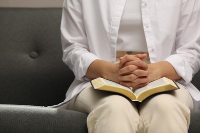 Religious woman praying over Bible indoors, closeup Photo of Religious woman praying over Bible indoors, closeup