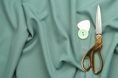 Scissors, button and tailor's chalk on green fabric, flat lay. Space for text Photo of Scissors, button and tailor's chalk on green fabric, flat lay. Space for text