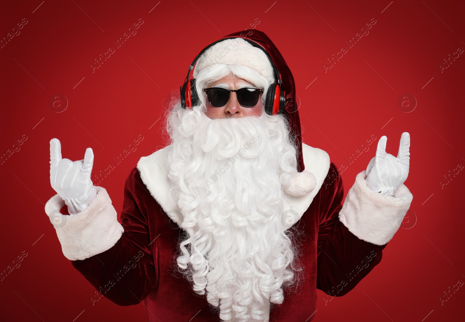 Photo of Santa Claus with headphones listening to Christmas music on red background