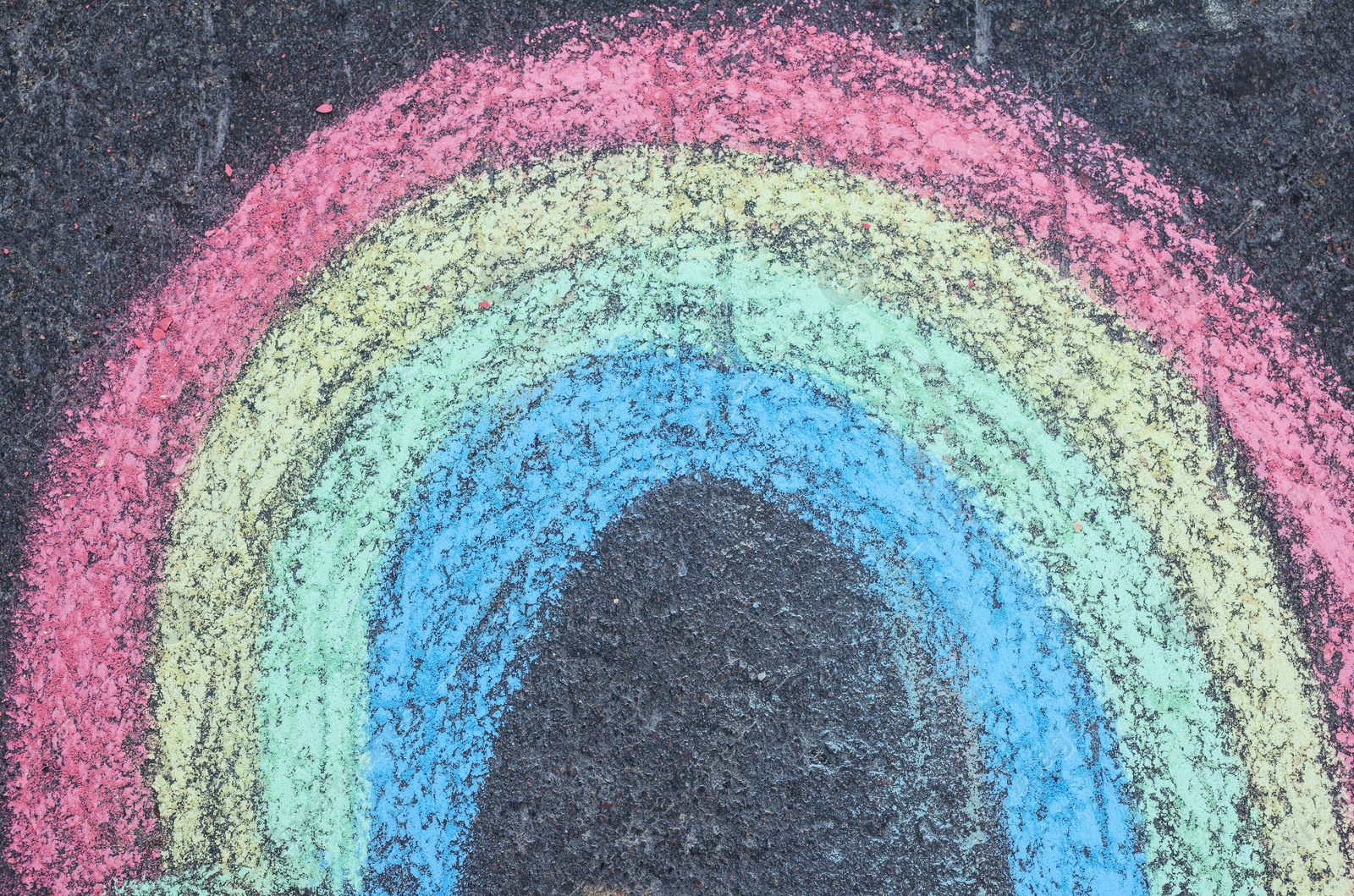 Photo of Child's chalk drawing of rainbow on asphalt, top view