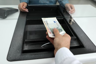 Cashier giving money to woman at currency exchange window in bank, closeup Photo of Cashier giving money to woman at currency exchange window in bank, closeup