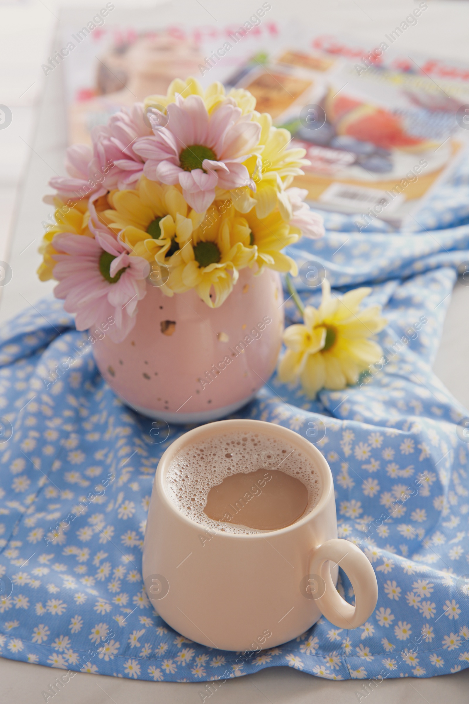 Cup of fresh coffee and beautiful bouquet on light blue printed cloth. Good morning Photo of Cup of fresh coffee and beautiful bouquet on light blue printed cloth. Good morning