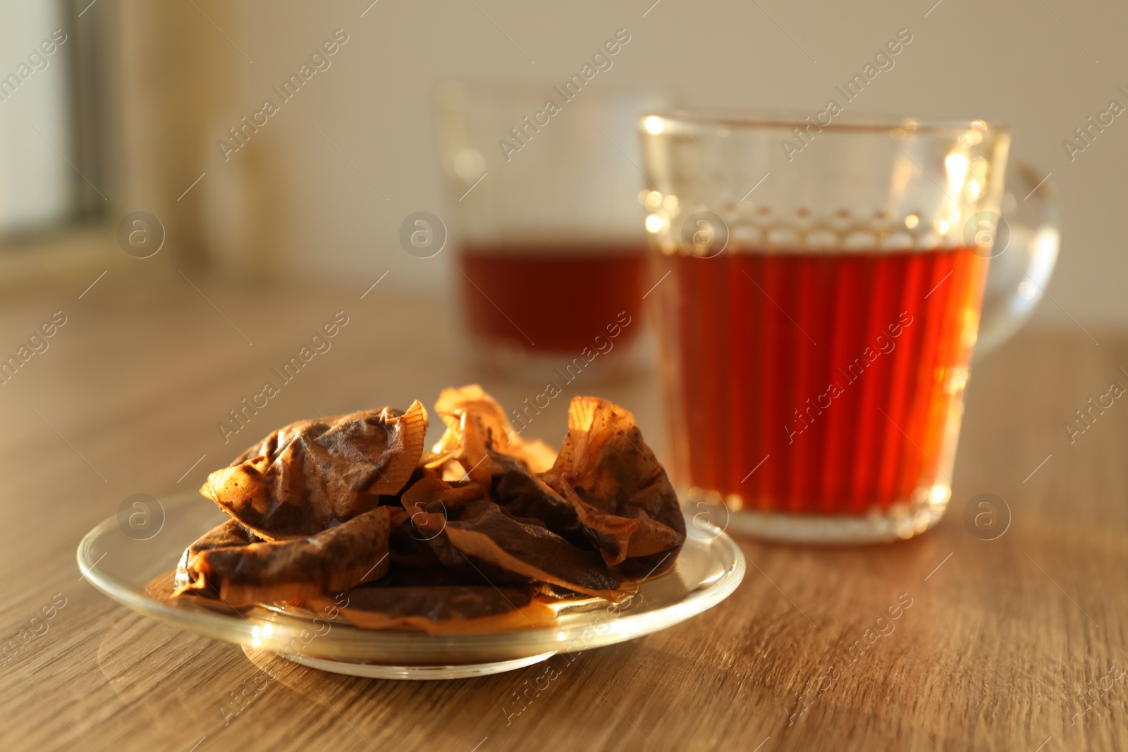 Glass saucer with used tea bags on wooden table Photo of Glass saucer with used tea bags on wooden table