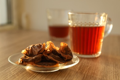 Glass saucer with used tea bags on wooden table Photo of Glass saucer with used tea bags on wooden table