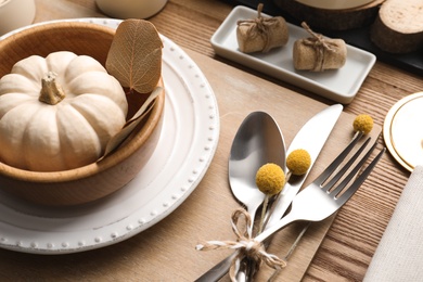 Autumn table setting with pumpkin and decor on wooden background Photo of Autumn table setting with pumpkin and decor on wooden background