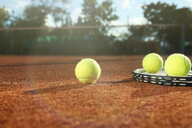 Tennis balls and racket on clay court Photo of Tennis balls and racket on clay court